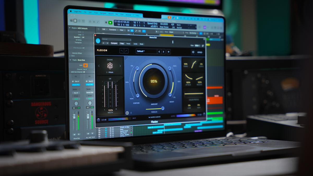 A laptop on a desk displaying a digital audio workstation interface, with audio equipment blurred in the background of a studio setting.
